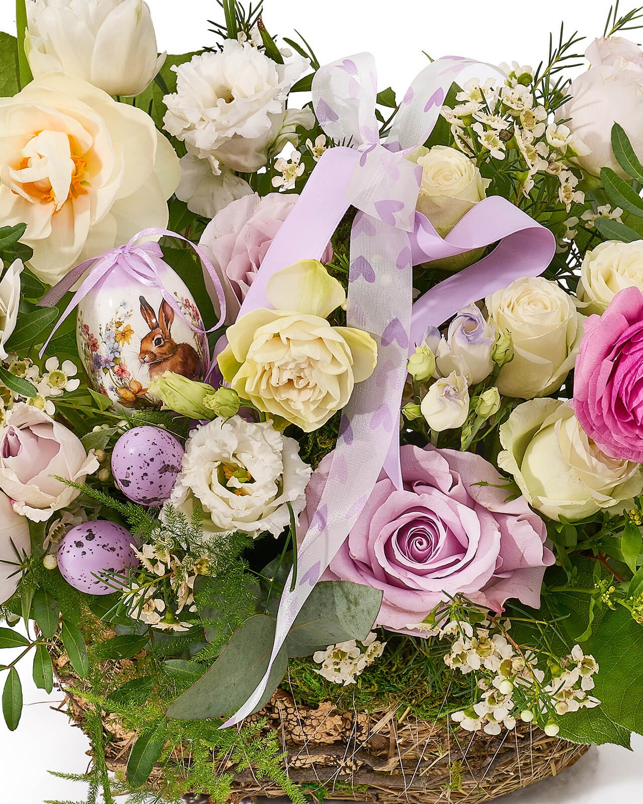 Aranjament floral in cos cu trandafiri mov, lalele albe, ranunculus, lisianthus si frezii albe „Meadow Glow”