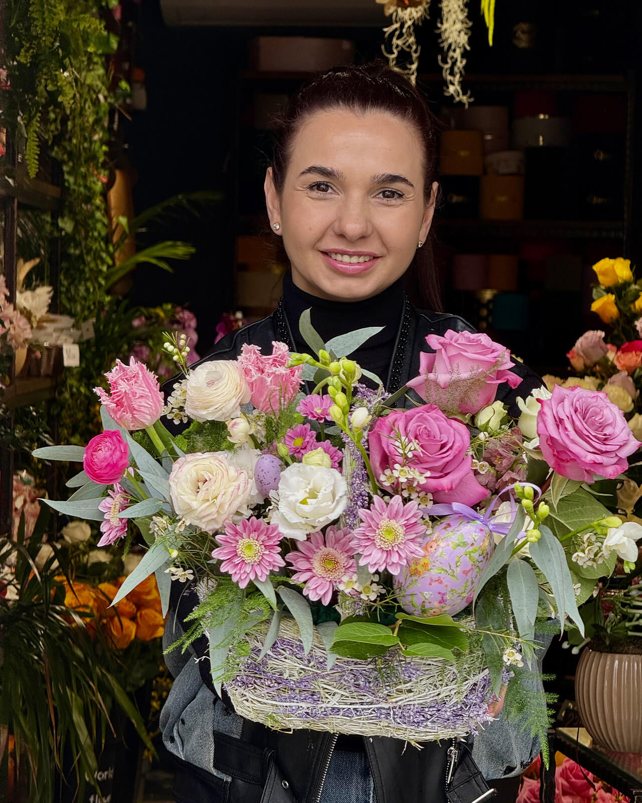 Aranjament floral in cos cu trandafiri mov, ranunculus alb, lalele roz, minirose si frezii albe „Blushing Petals”