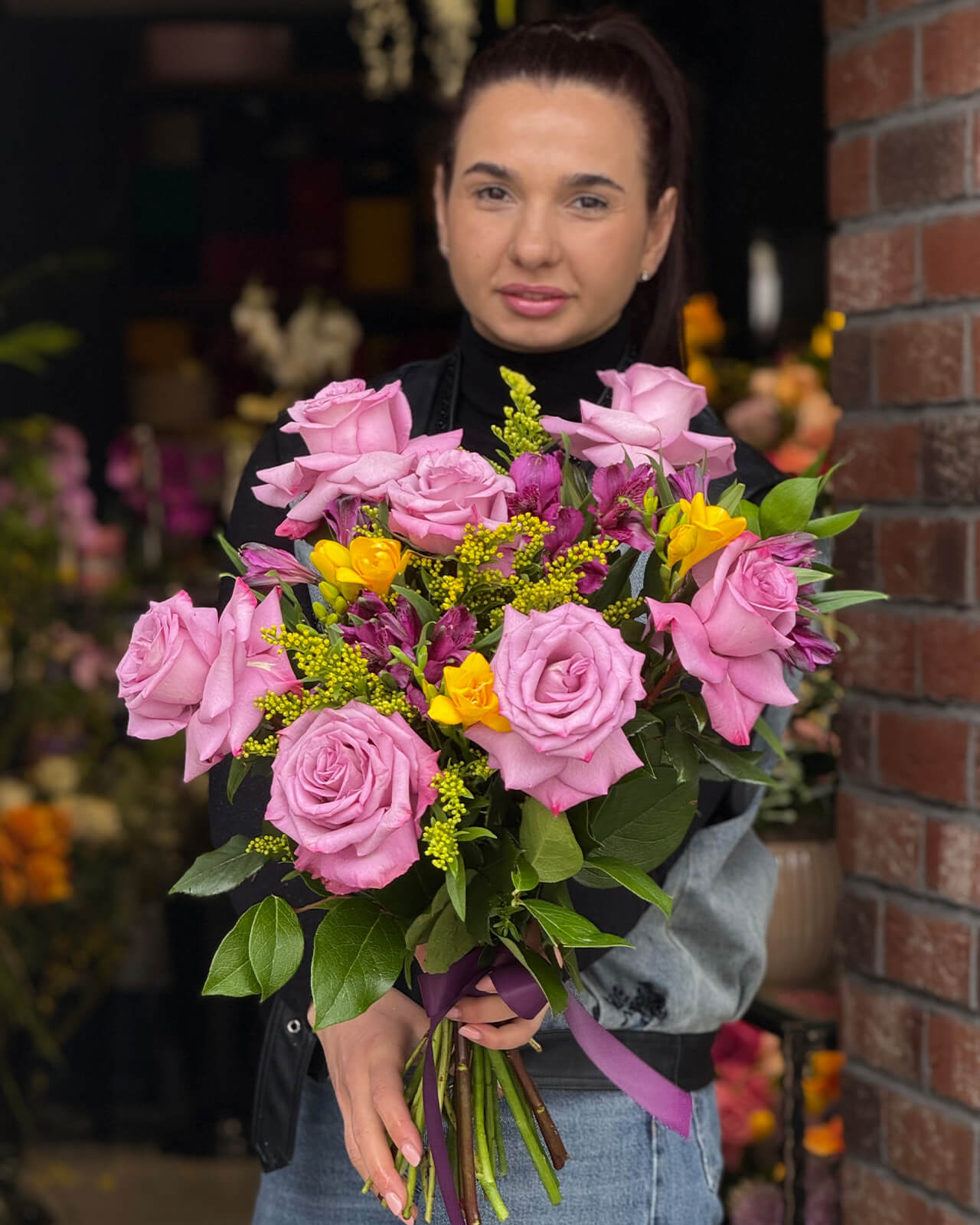 Buchet cu trandafiri mov, alstroemeria mov, frezii galbene, solidago si ruscus „Lavender Gleam”